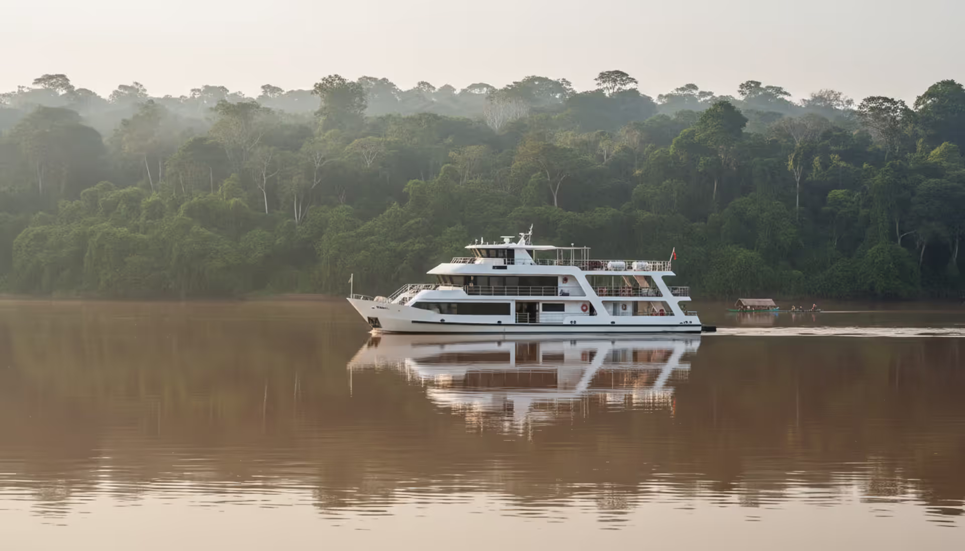 Luxury expedition cruise ship anchored on the Amazon River surrounded by dense tropical rainforest at sunrise with mist over calm brown water