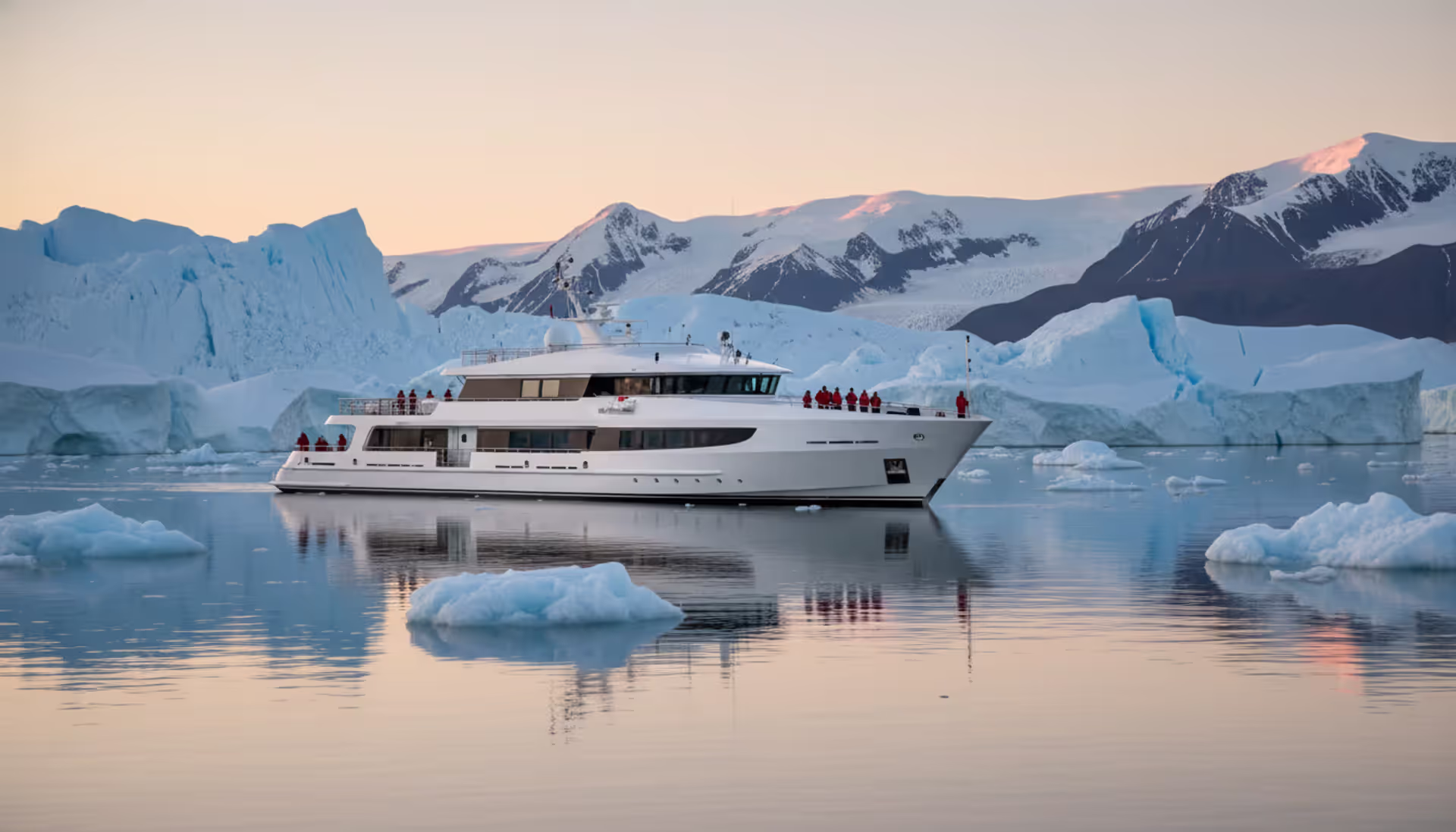 Luxury expedition cruise ship anchored in a calm Arctic fjord surrounded by blue icebergs and snow-covered mountains under midnight sun