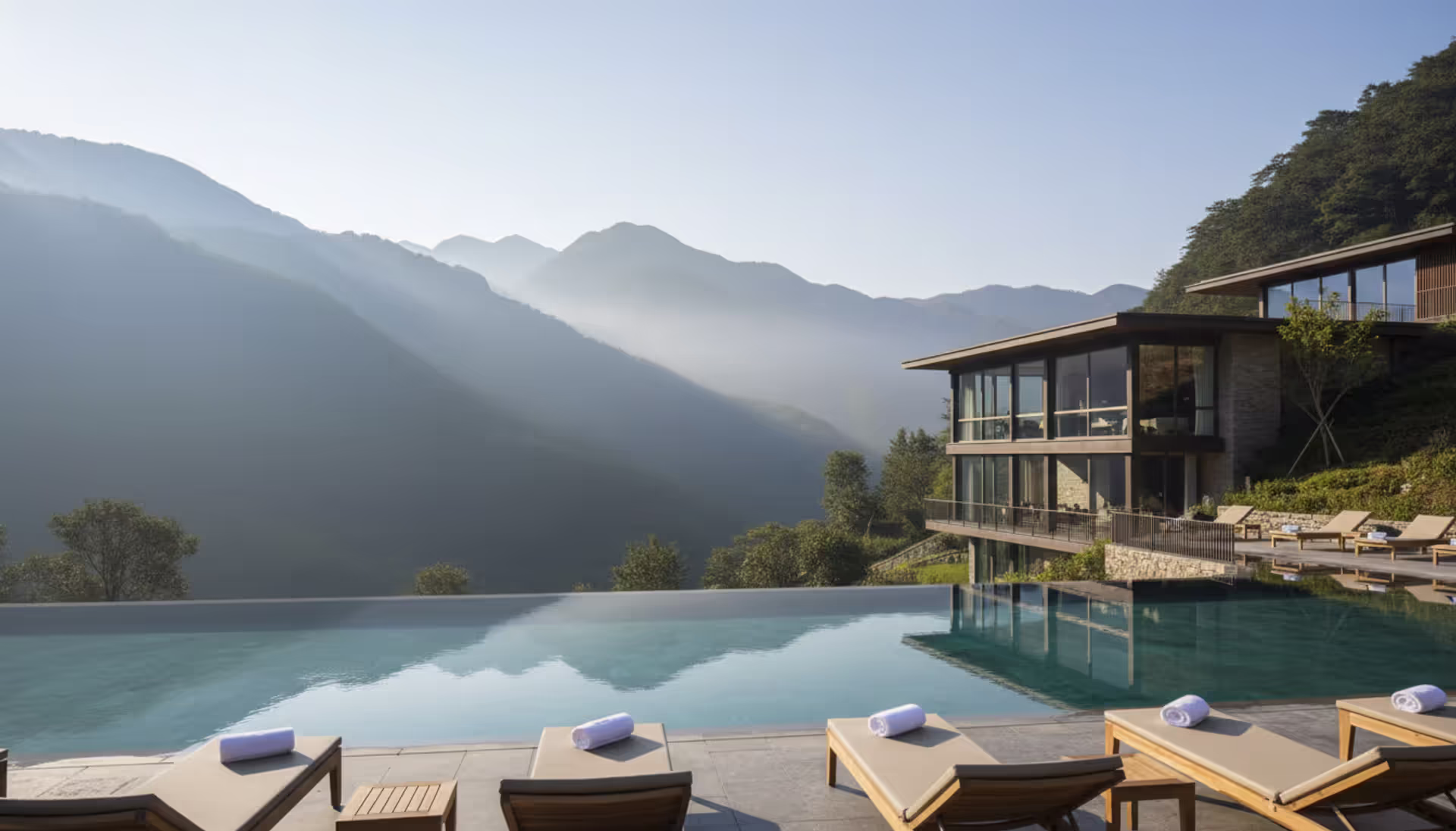 Luxury wellness retreat infinity pool surrounded by mountains at sunrise with modern architecture building in natural landscape