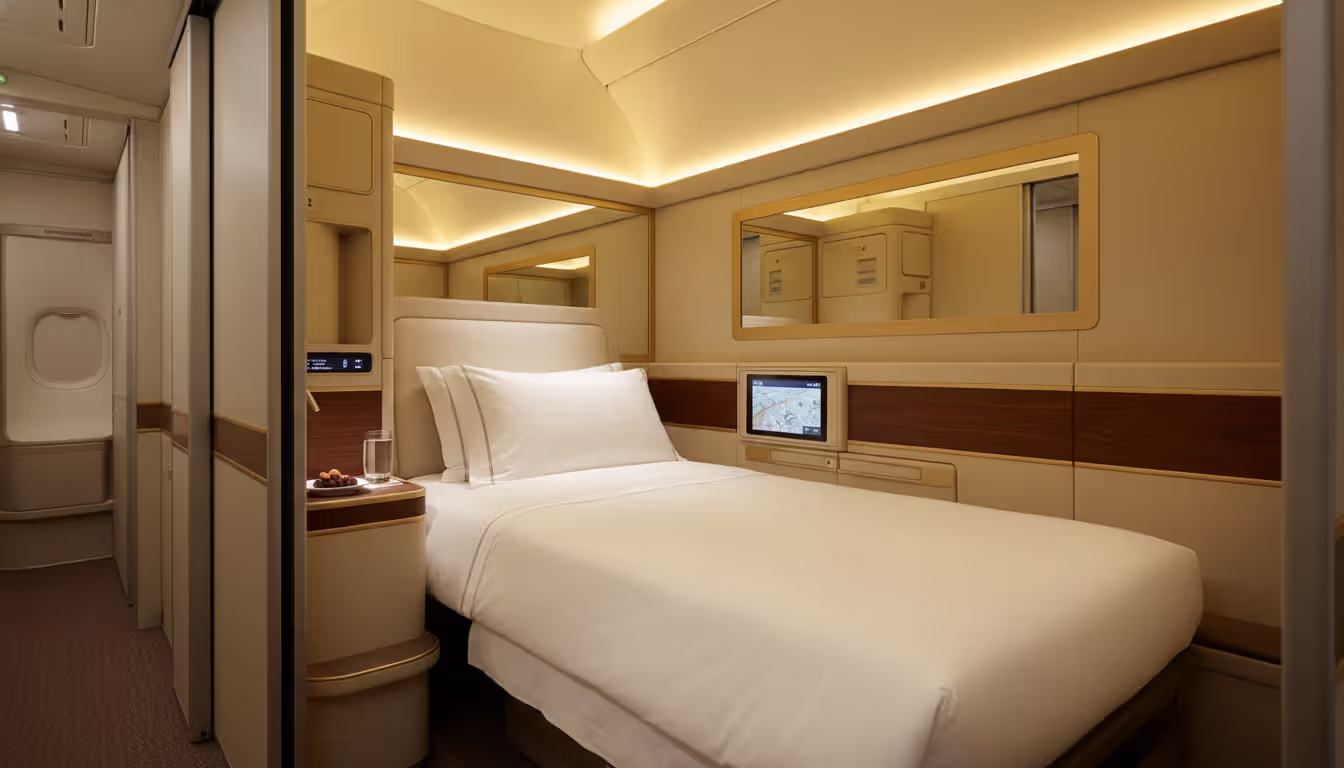 Emirates first class private suite on Airbus A380 with floor to ceiling doors, flat bed, mirror, warm golden lighting and wood-finish details